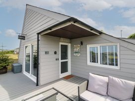 The exterior entrance of a gray wooden house with a sliding glass door a small sofa and table on the deck at La Bella Vista in Kilkhampton