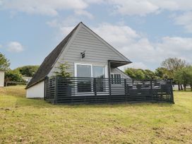 An exterior view of an a-frame house with a black fenced porch on a grassy area at La Bella Vista in Kilkhampton