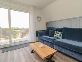 A living room with a blue sofa a wooden coffee table and large sliding glass doors at La Bella Vista in Kilkhampton