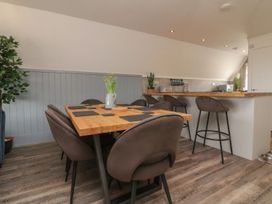 A dining area with a wooden table and six chairs next to a kitchen counter with bar stools at La Bella Vista in Kilkhampton