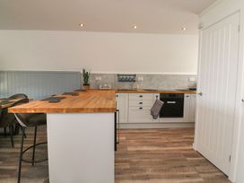 A kitchen with wooden countertops white cabinets a toaster kettle and a white door at La Bella Vista in Kilkhampton