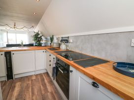 A modern kitchen with wooden countertops white cabinets black stove and oven and plants near a window at La Bella Vista in Kilkhampton