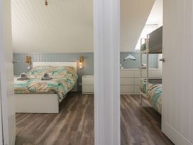 Two bedrooms separated by a wall one with a double bed and nightstands the other with bunk beds and a dresser at La Bella Vista in Kilkhampton