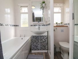A bathroom with a bathtub sink with mosaic cabinet and a toilet with small potted plants at La Bella Vista in Kilkhampton