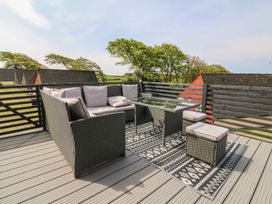 An outdoor patio with a wicker sofa and chairs around a glass table on a patterned rug at La Bella Vista in Kilkhampton