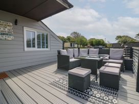 An outdoor deck with a seating area including a corner sofa table and four cushioned stools at La Bella Vista in Kilkhampton
