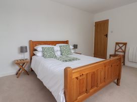 A bedroom with a bed, bedside lamp, and chair at Pear Tree Cottage in Great Ouseburn