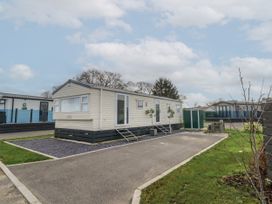 A residential park with a beige mobile home on a paved lot and small green shed at Dunlin Walk 13 Hayling Island