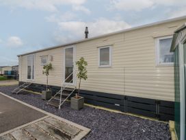 The exterior of a beige mobile home with two steps leading to two doors and potted plants outside at Dunlin Walk 13 Hayling Island