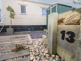 Exterior of a mobile home with wooden steps stones and a planter with a small tree at Dunlin Walk 13 in Hayling Island