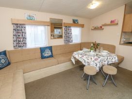 A dining area with a table set for four and corner seating with cushions at Dunlin Walk 13 Hayling Island