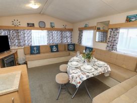 A living room with a beige corner sofa a table set for four and a television at Dunlin Walk 13 Hayling Island