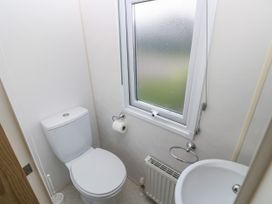 A small bathroom with a toilet sink radiator and frosted window at Dunlin Walk 13 Hayling Island