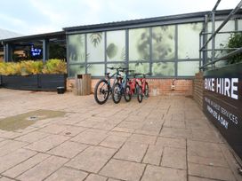 An outdoor area with bicycles parked next to a frosted glass wall and a sign for bike hire at Dunlin Walk 13 in Hayling Island