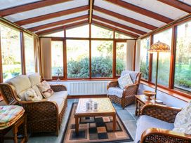 A conservatory with seating and windows at Maggie's Barn in Brecon