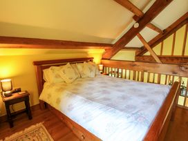A bedroom with a wooden bed and bedside table at Maggie's Barn Brecon