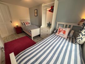 A bedroom with two beds and a wardrobe at The Packing House in Rosudgeon
