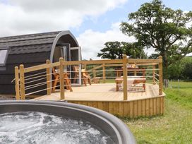 An outdoor area with a deck, hot tub, and seating at Under Oak Pod in Totnes