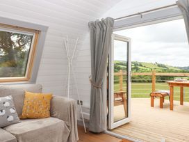 A living room with a sofa and a view of the outside deck at Under Oak Pod in Totnes