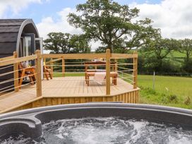 An outdoor deck with a hot tub, table, and chairs at Under Oak Pod in Totnes