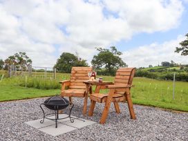 An outdoor seating area with wooden chairs and a fire pit at Under Oak Pod in Totnes