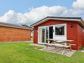 A cabin with a picnic table and grass at H2 Atlantic Bay Holiday Park in Padstow