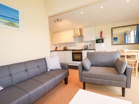 A living room with a sofa and kitchen area at 161 Atlantic Bay Holiday Park in Padstow