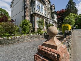 A stone and brick house with a gravel driveway and garden at Sunnycroft in Keswick