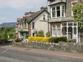 A row of stone and brick houses with a hedge and stone wall along a roadside at Sunnycroft in Keswick