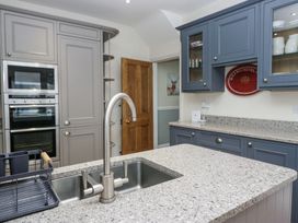 A kitchen with a double sink and faucet on a stone countertop with built in ovens and blue and gray cabinets at Sunnycroft in Keswick