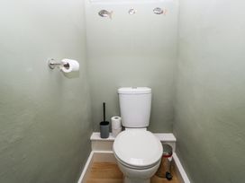 A small bathroom with a toilet a toilet brush a trash can and a toilet paper holder with a roll at Sunnycroft in Keswick