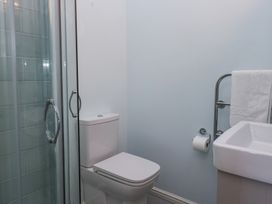 A bathroom with a toilet next to a glass shower enclosure and a sink with a towel rail at Sunnycroft in Keswick