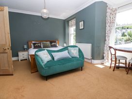 A bedroom with a double bed green sofa wooden table and chairs at Sunnycroft in Keswick