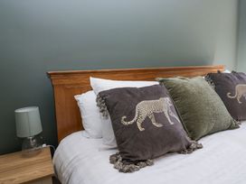 A bed with wooden headboard and decorative pillows with animal designs and fringes beside a bedside table with a lamp