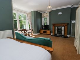A bedroom with a bed sofa table chairs fireplace and wardrobe at Sunnycroft in Keswick