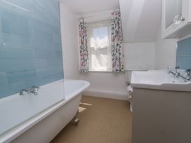 A bathroom with a bathtub sink and window with floral curtains at Sunnycroft in Keswick