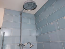 A shower area with blue tiled walls and a large round showerhead at Sunnycroft in Keswick