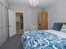 A bedroom with a bed covered in blue and white bedding near wooden and white doors at Sunnycroft in Keswick
