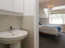 A bathroom sink with faucet next to a bedroom with a bed and window at Sunnycroft in Keswick
