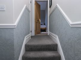 A carpeted staircase with decorative wall panels leading to a room with an open wooden door and a bed visible at Sunnycroft in Keswick