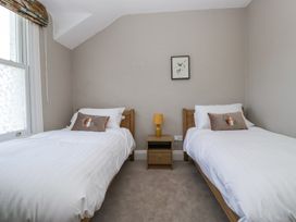 A bedroom with two single beds a nightstand with a lamp and a framed picture on the wall at Sunnycroft in Keswick
