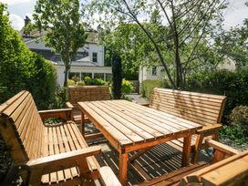 An outdoor seating area with wooden benches and a table in a garden at Sunnycroft in Keswick