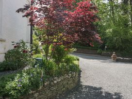 A garden with a red-leaved tree and flower bed beside a gravel driveway at Sunnycroft in Keswick