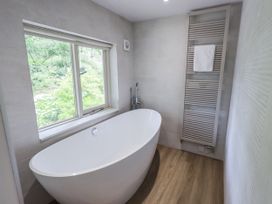 A bathroom with a bathtub and window at Rowanhill in Kendal