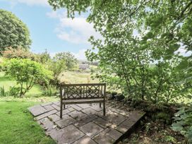 A garden with a stone patio and bench at Rowanhill, Kendal
