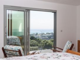 A bedroom with a bed and chairs overlooking a view at Seacroft in Torquay