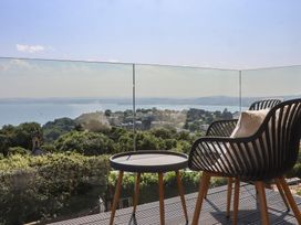 An outdoor balcony with a chair and table overlooking a coastal view at Seacroft in Torquay