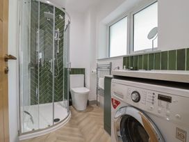A bathroom with a shower, toilet, washing machine, and sink at Seacroft in Wellswood near Torquay