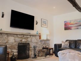 A living room with a tv and a stone fireplace at The Little Farmhouse in Carnforth