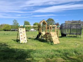 A playground with climbing wall, swings, slide, and trampoline at The Little Farmhouse in Carnforth
